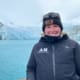 A woman on a boat with a glacier in the background.